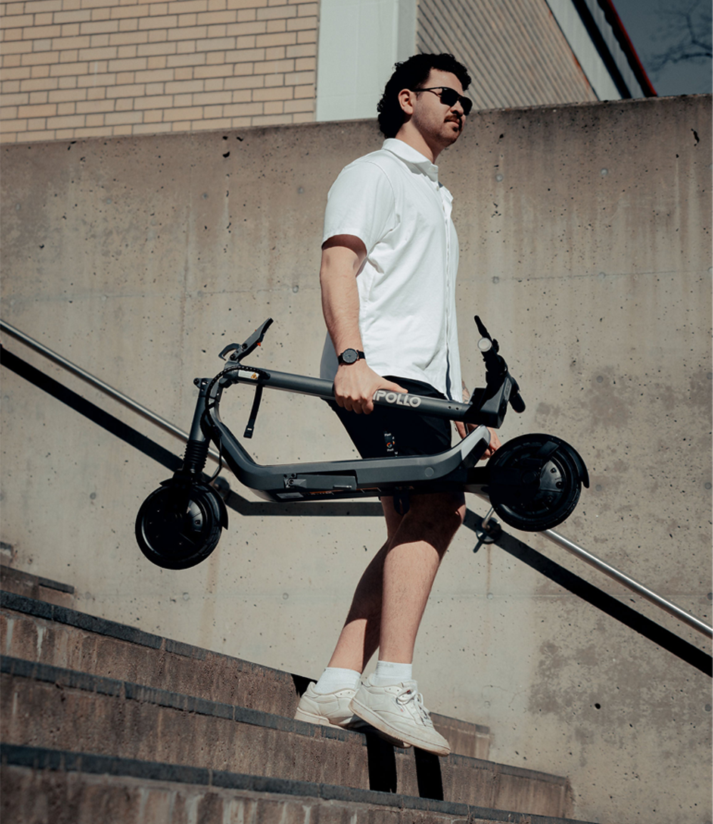 Apollo Go 2024 electric scooter carried down urban steps.