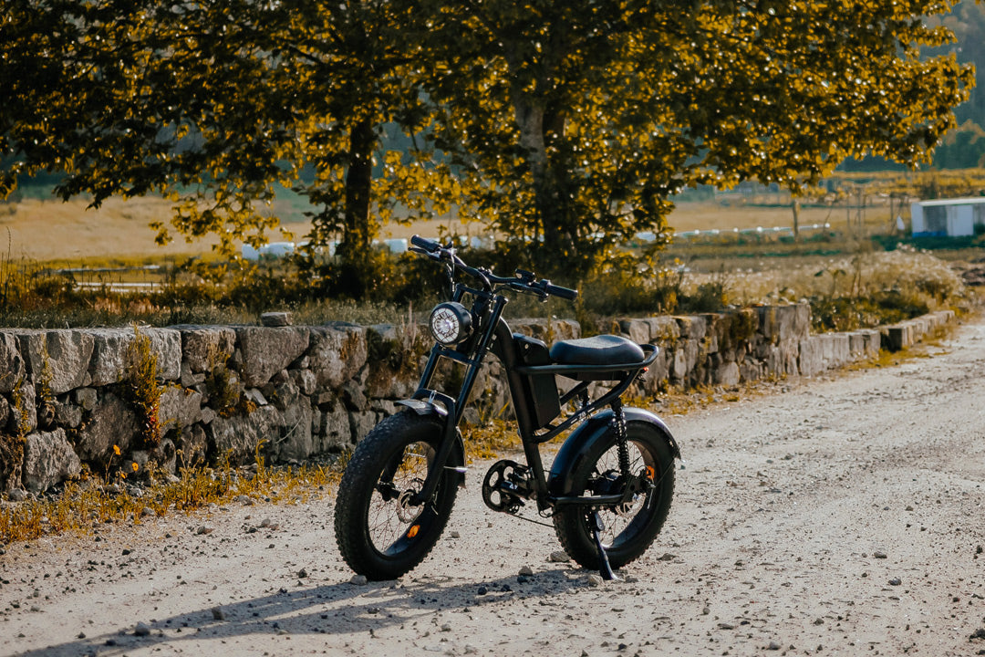 Black electric bike Z8 on a dirt road with trees and stone wall in the background