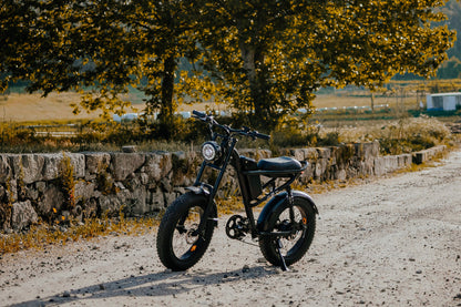 Black electric bike Z8 on a dirt road with trees and stone wall in the background